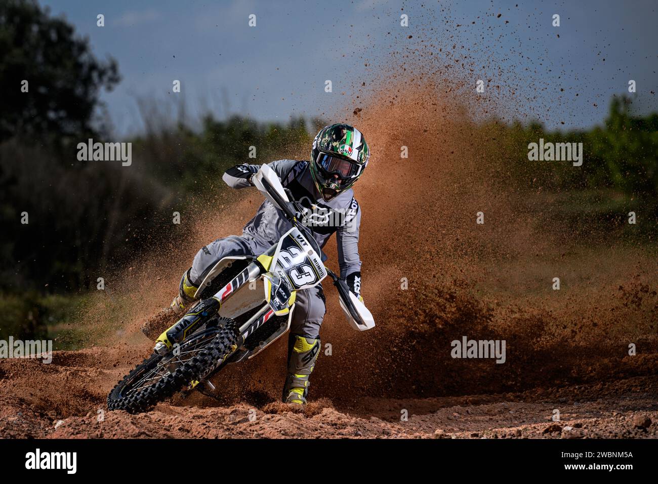 Motocross rider in action with speed to camera and lifting mud, rocks ...