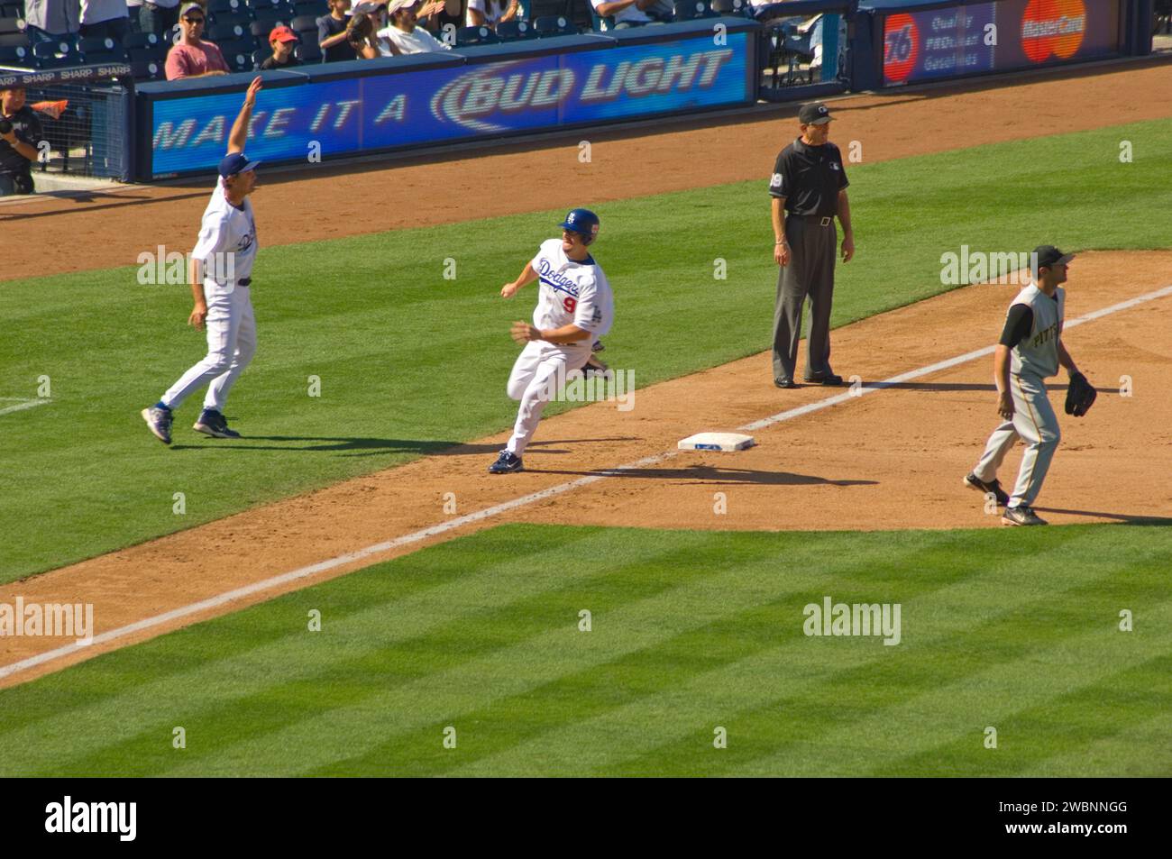 A baserunner rounding third base and heading for home to score a run in a Major League game at Dodger Stadium in Los Angeles, California, USA Stock Photo