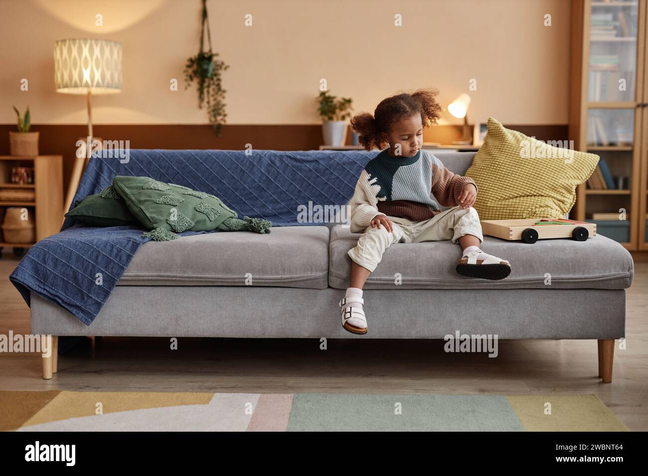 Little Girl Sitting on Sofa at Home Stock Photo