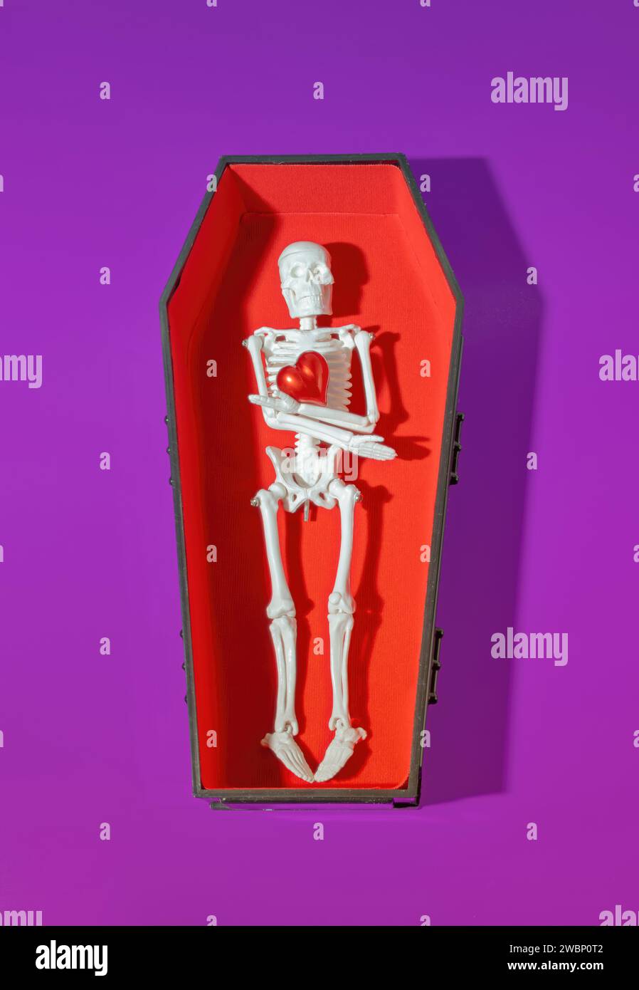 A Skeleton Laying in Open Coffin Holding a Red Heart Stock Photo - Alamy