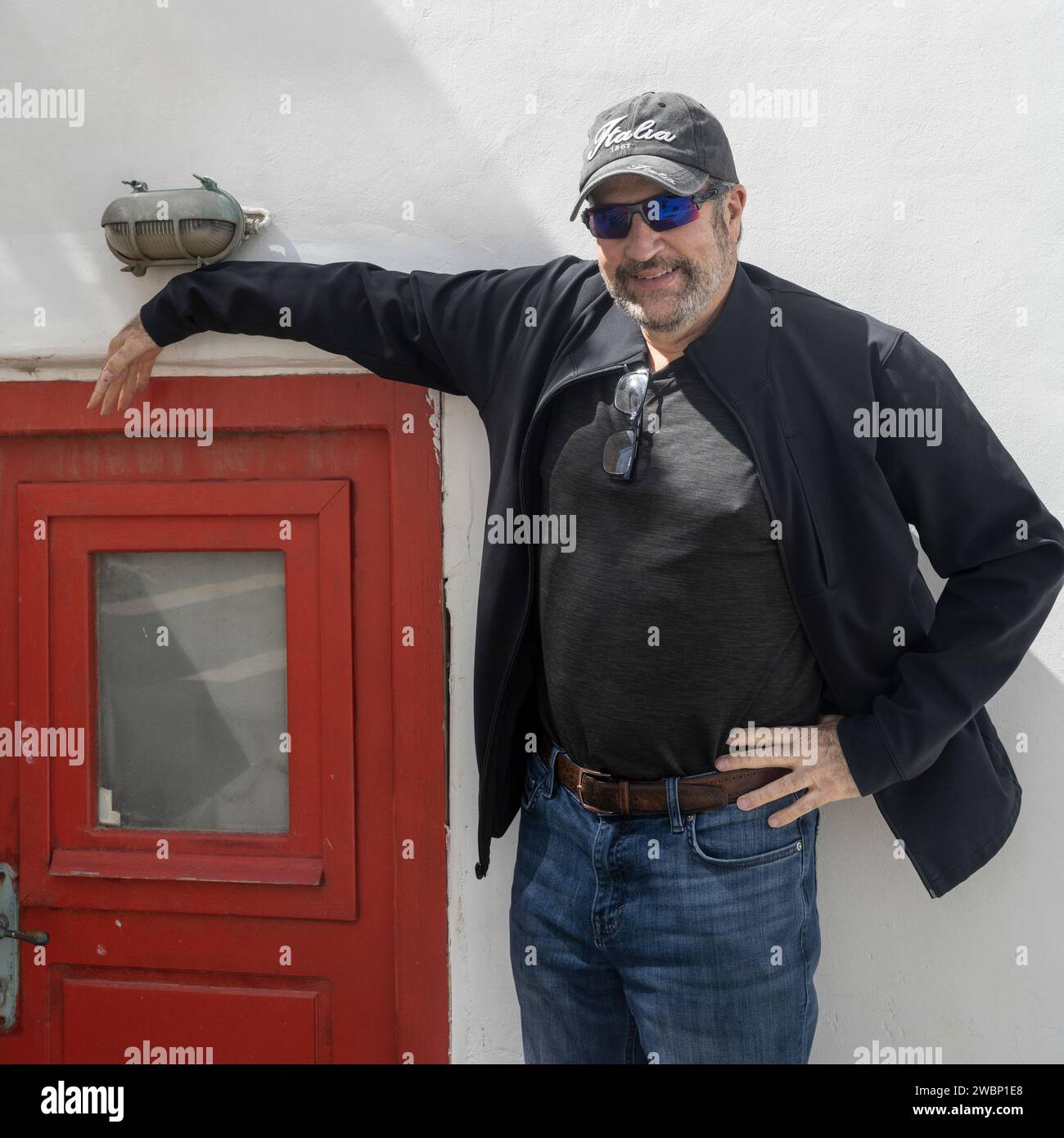 Male tourist leaning against a wall, Ano Mera, Mykonos Island, Greece Stock Photo