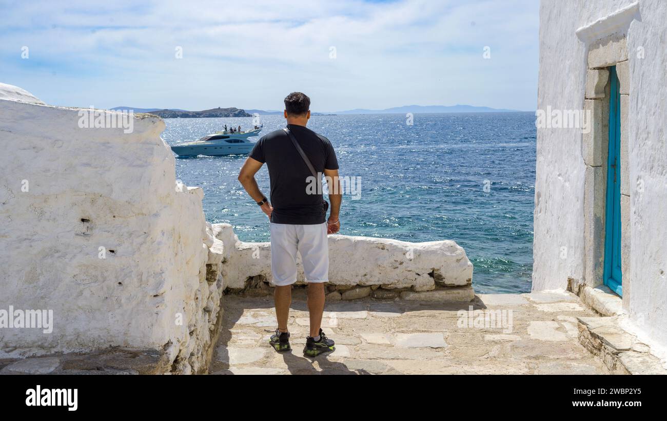 Male tourist looking at the Aegean Sea on Mykonos Island, Greece Stock Photo