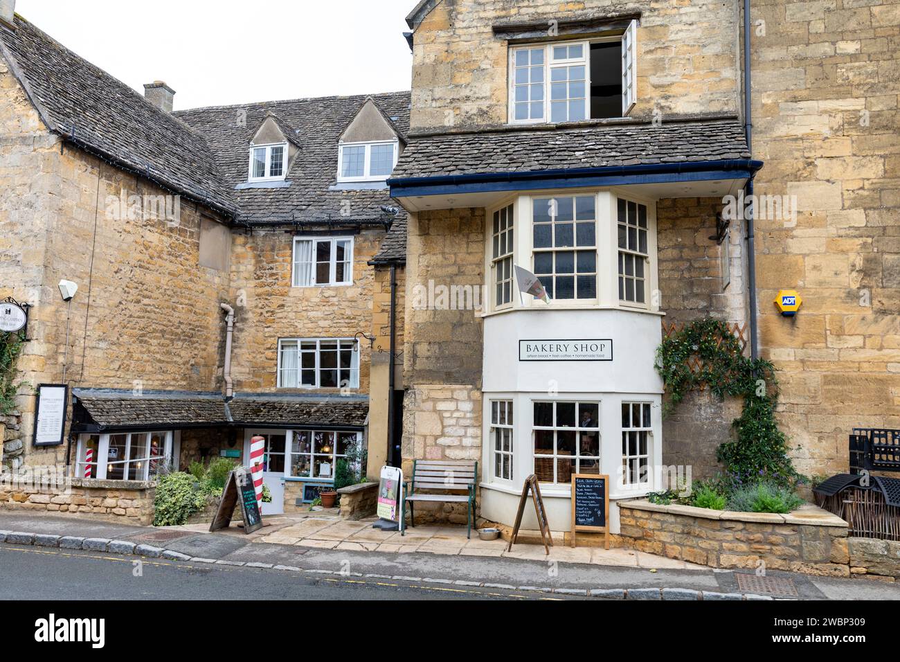 Chipping Campden, lower high street in this market town with Huxleys bakery store and adjacent barbers shop, Gloucestershire,England,UK,2023 Stock Photo