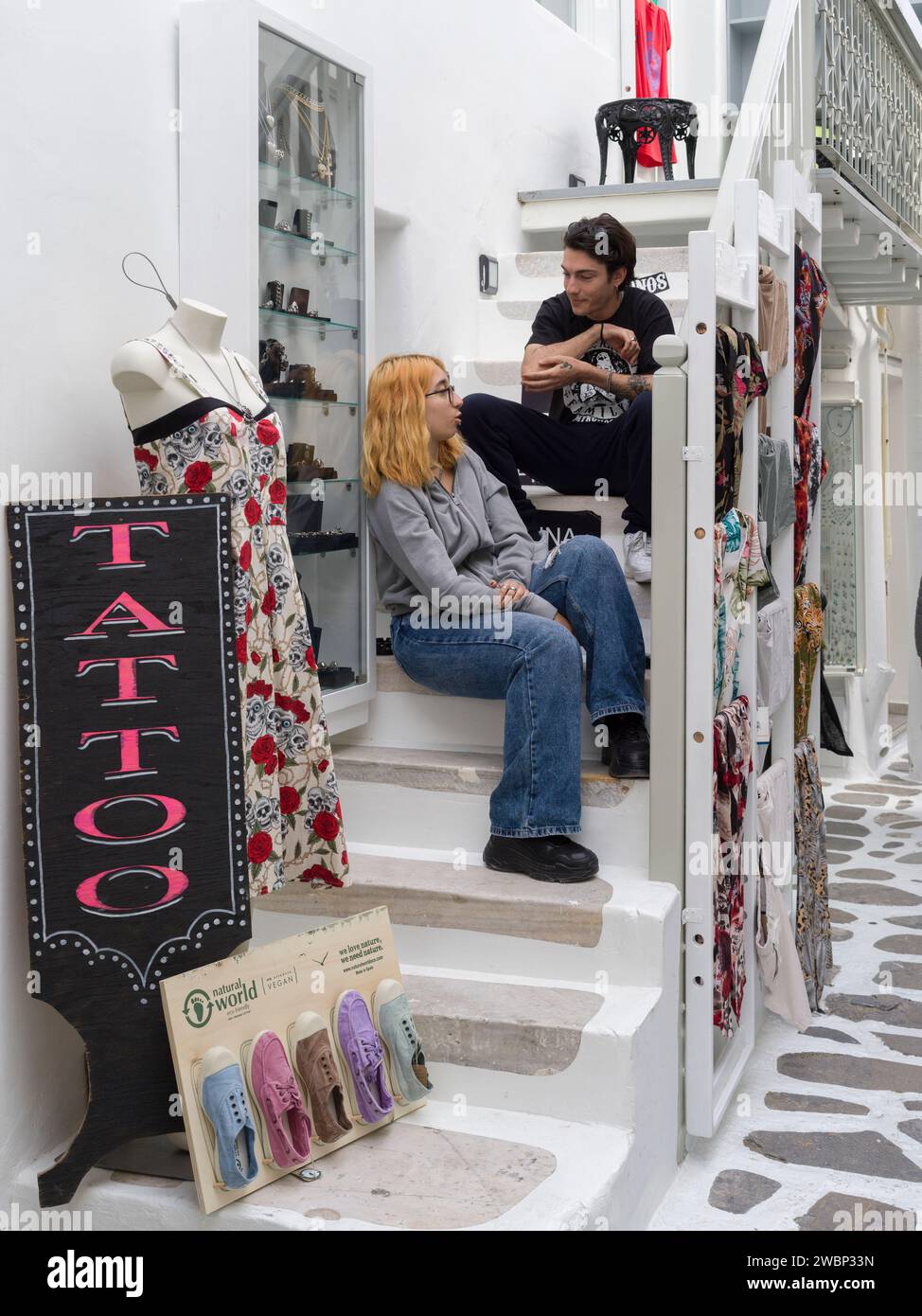 A couple sitting on the stairway of a shop in Mykonos Town, Mykonos Island, Greece Stock Photo