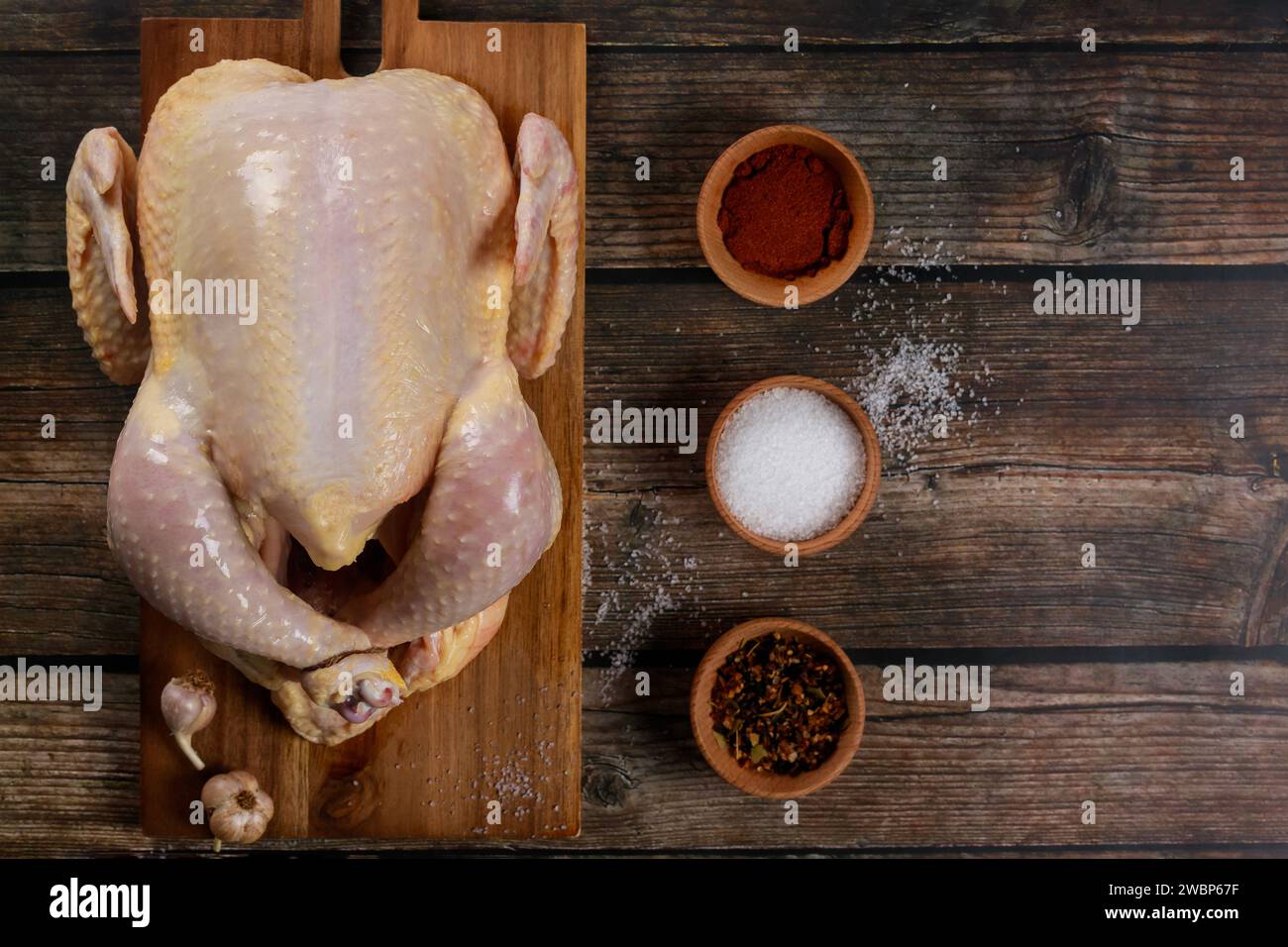 Cooking spices are accompanying the raw chicken on cutting board. Stock Photo