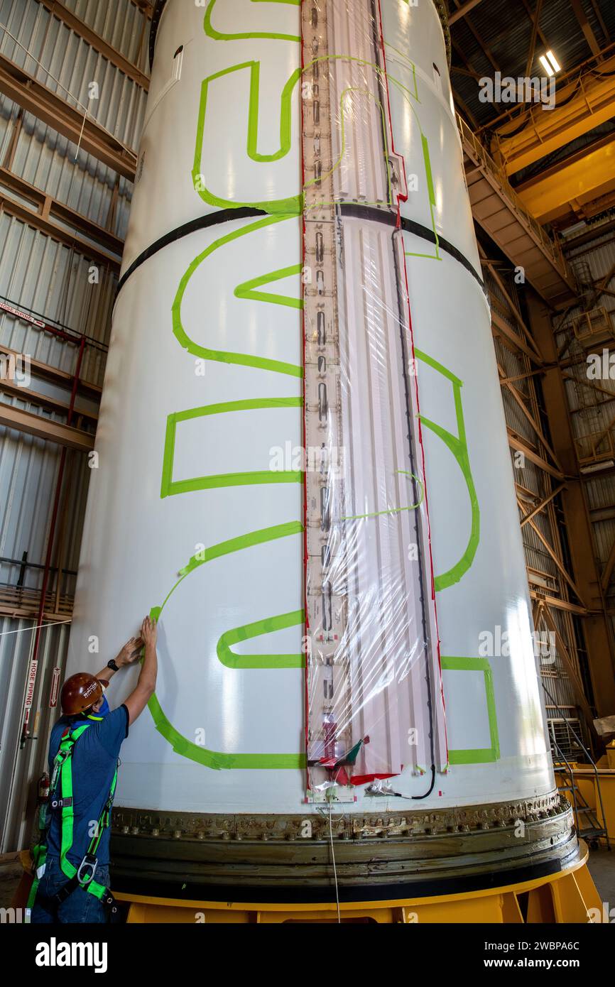 Workers with NASA’s Exploration Ground Systems (EGS) use a laser projector and green tape to mask off the shape of the agency’s “worm” logo on the side of an Artemis I solid rocket booster segment inside the Rotation, Processing and Surge Facility (RPSF) at Kennedy Space Center in Florida, Sept. 3, 2020. The booster segments will help propel the Space Launch System (SLS) rocket on Artemis I, a test of the Orion spacecraft and SLS as an integrated system ahead of crewed flights to the Moon. Northrop Grumman, which built the booster segments, is covering the cost of the painting. Stock Photo