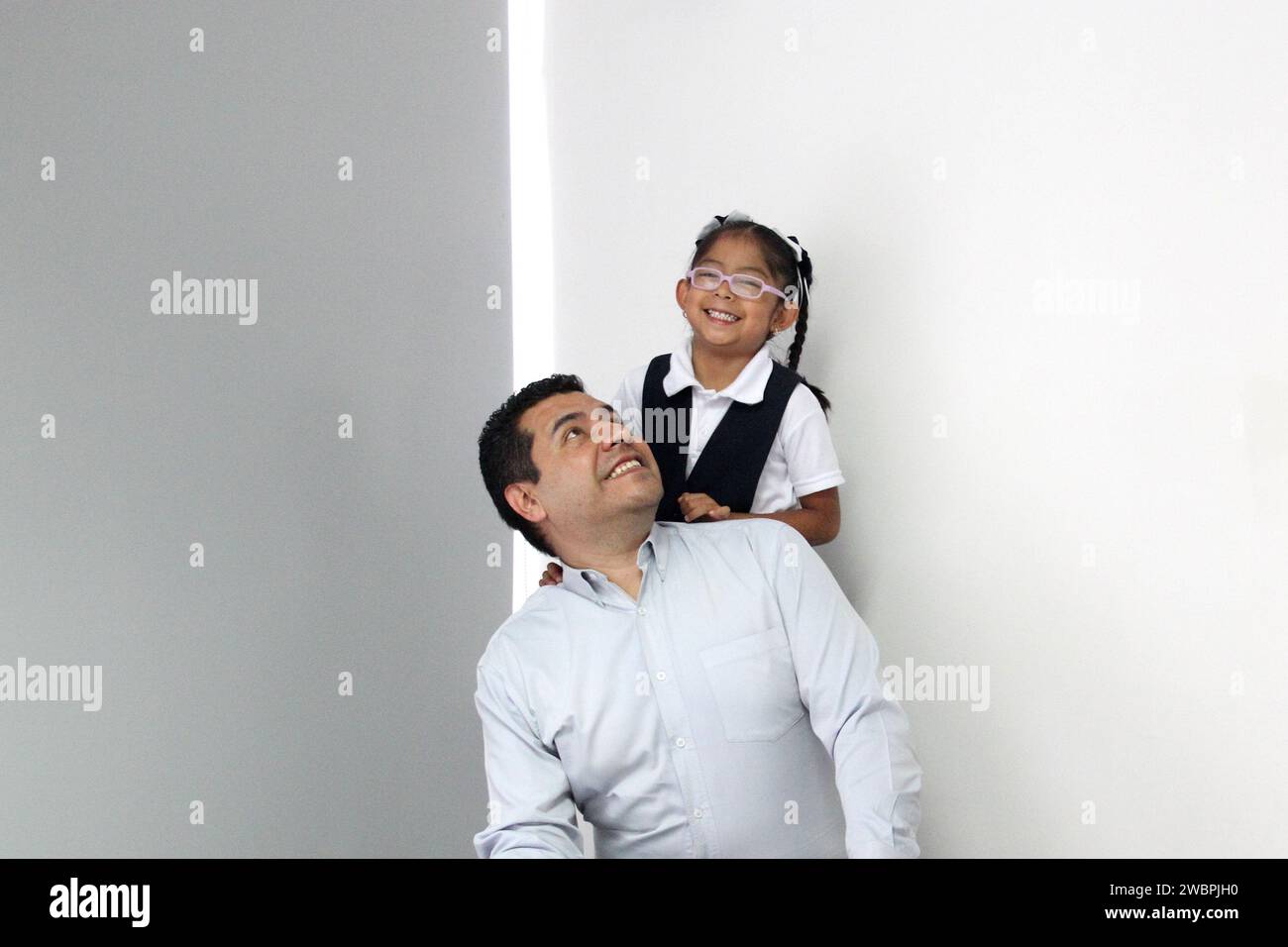 Divorced single dad with his 5 year old daughter in uniform dark Latinos play, have fun and spend quality time after school Stock Photo