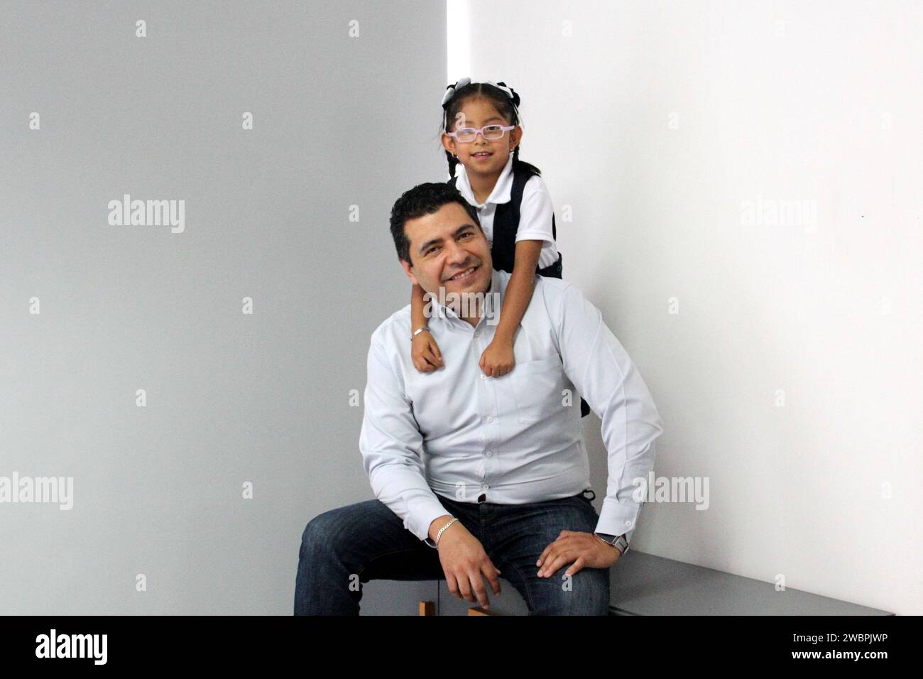 Divorced single dad with his 5 year old daughter in uniform dark Latinos play, have fun and spend quality time after school Stock Photo