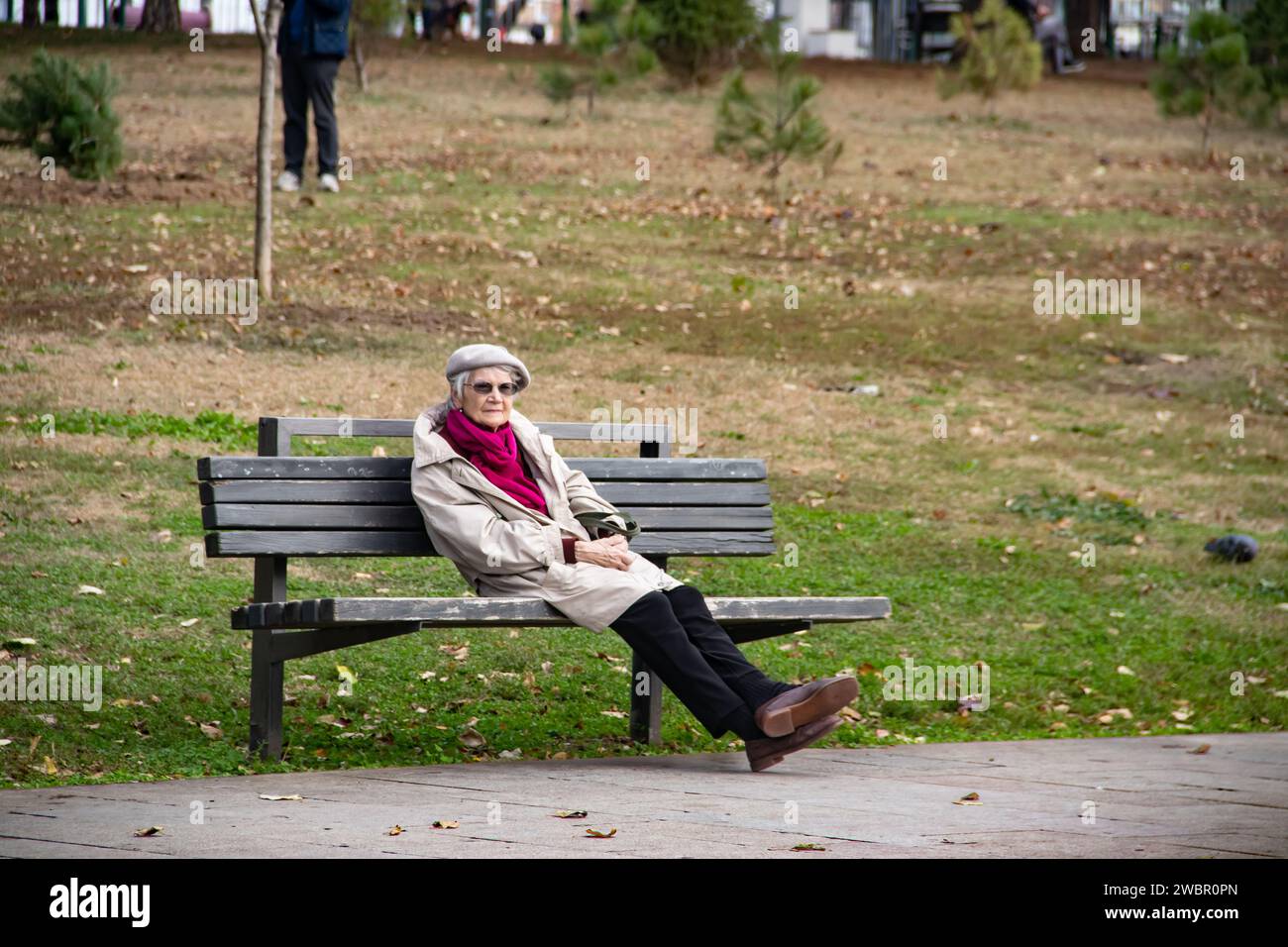 Lonely elder lady enjoying alone at the bench in city park (named Tasmajdan) in Belgrade Stock Photo