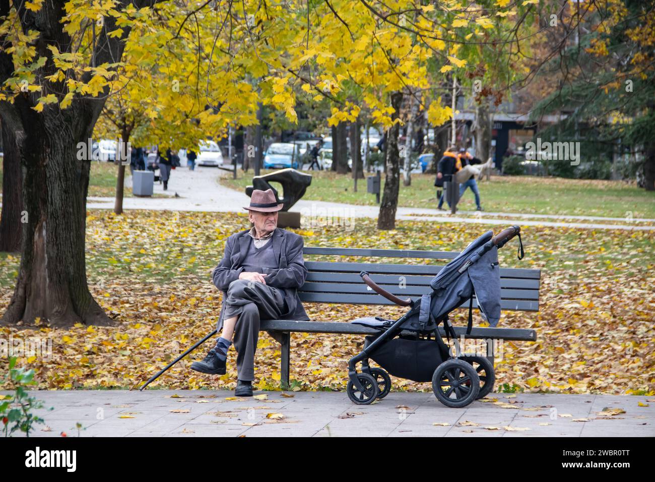 Grandfather taking grandchild for a walk resting at the bench in public city park Stock Photo
