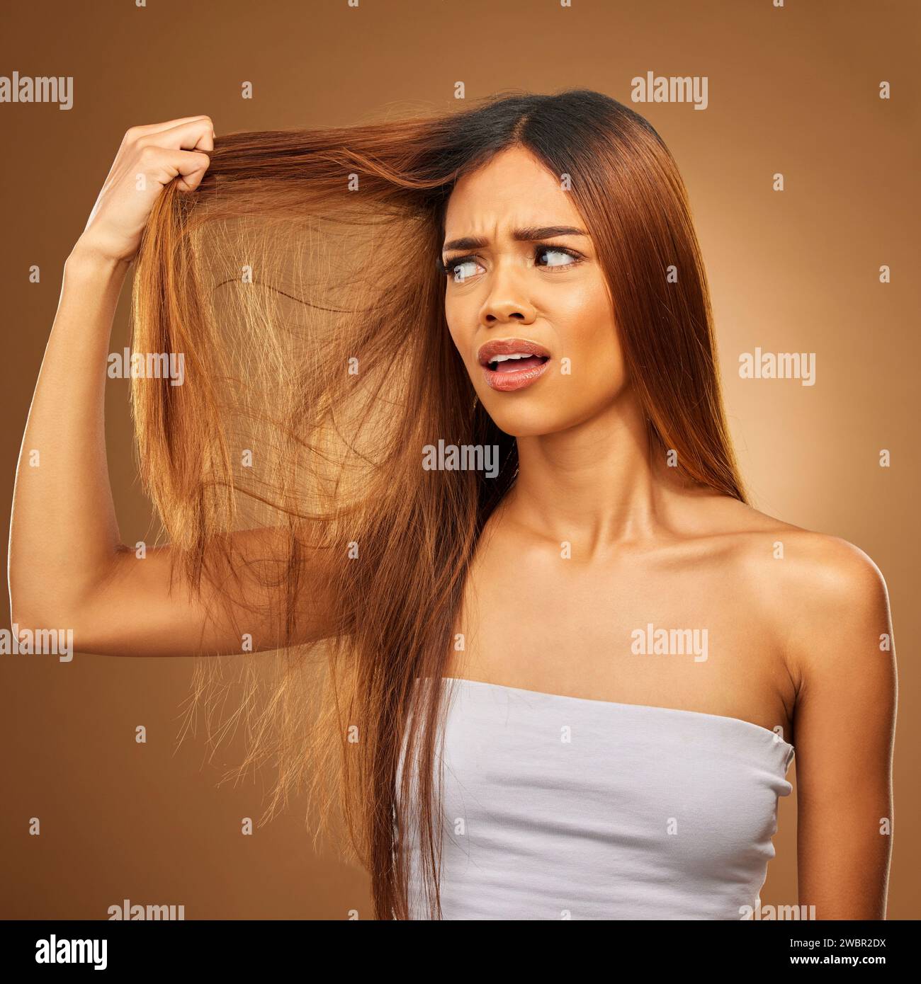 Hair, problem and woman in studio frustrated with hair loss, split ends or damage against a brown background. Haircare, crisis and girl model with Stock Photo