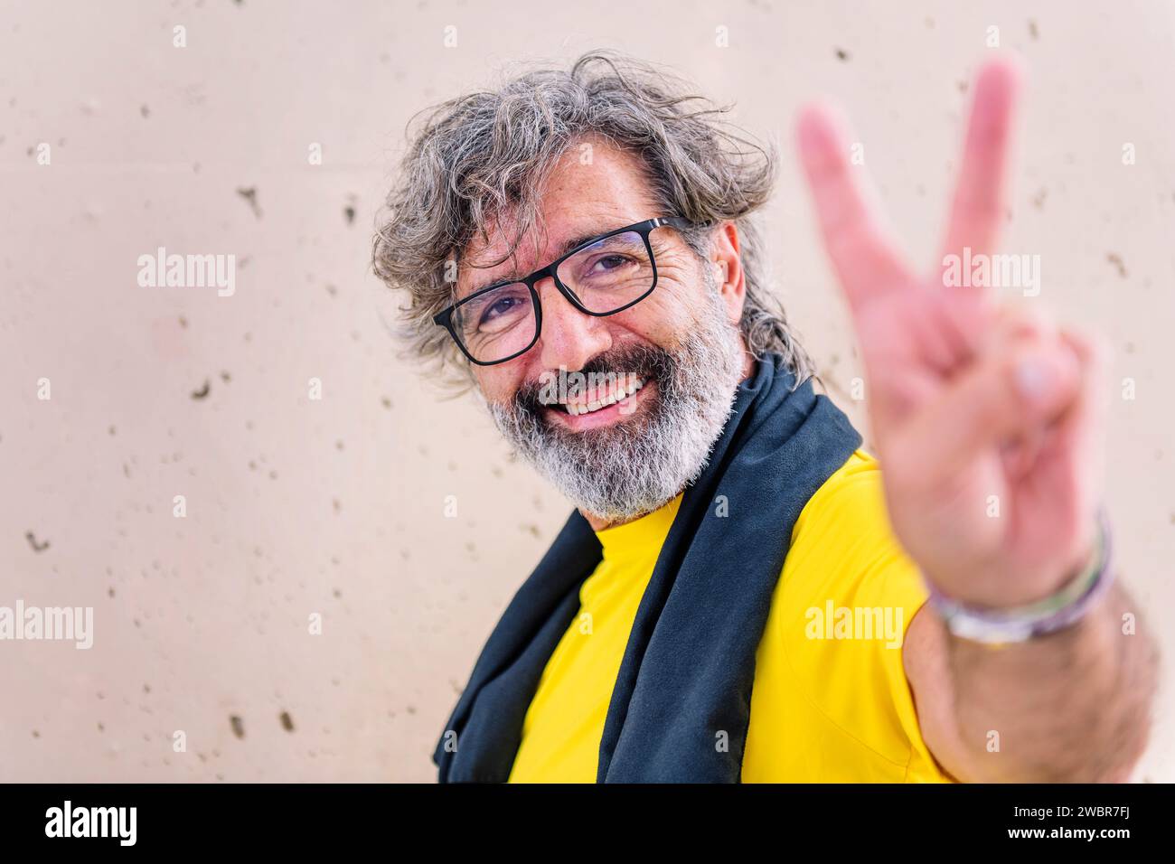 senior man smiling doing victory sign with hand Stock Photo