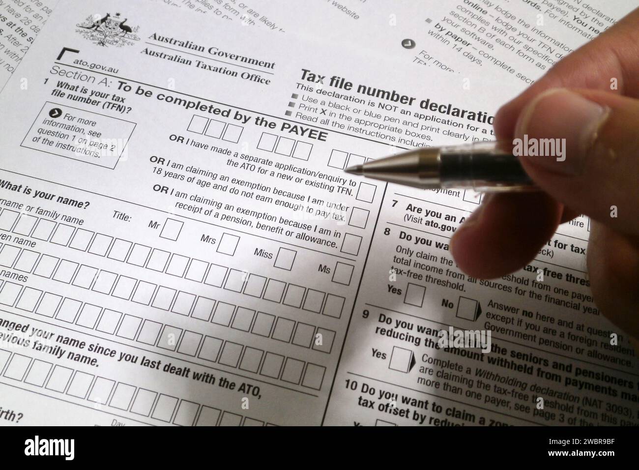 A pen hold by the fingers of somebody ready to fill an Australian Tax