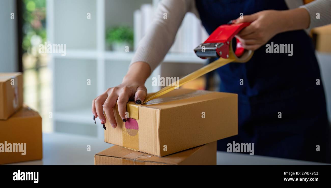 Woman use scotch tape to attach parcel box to prepare goods for the ...