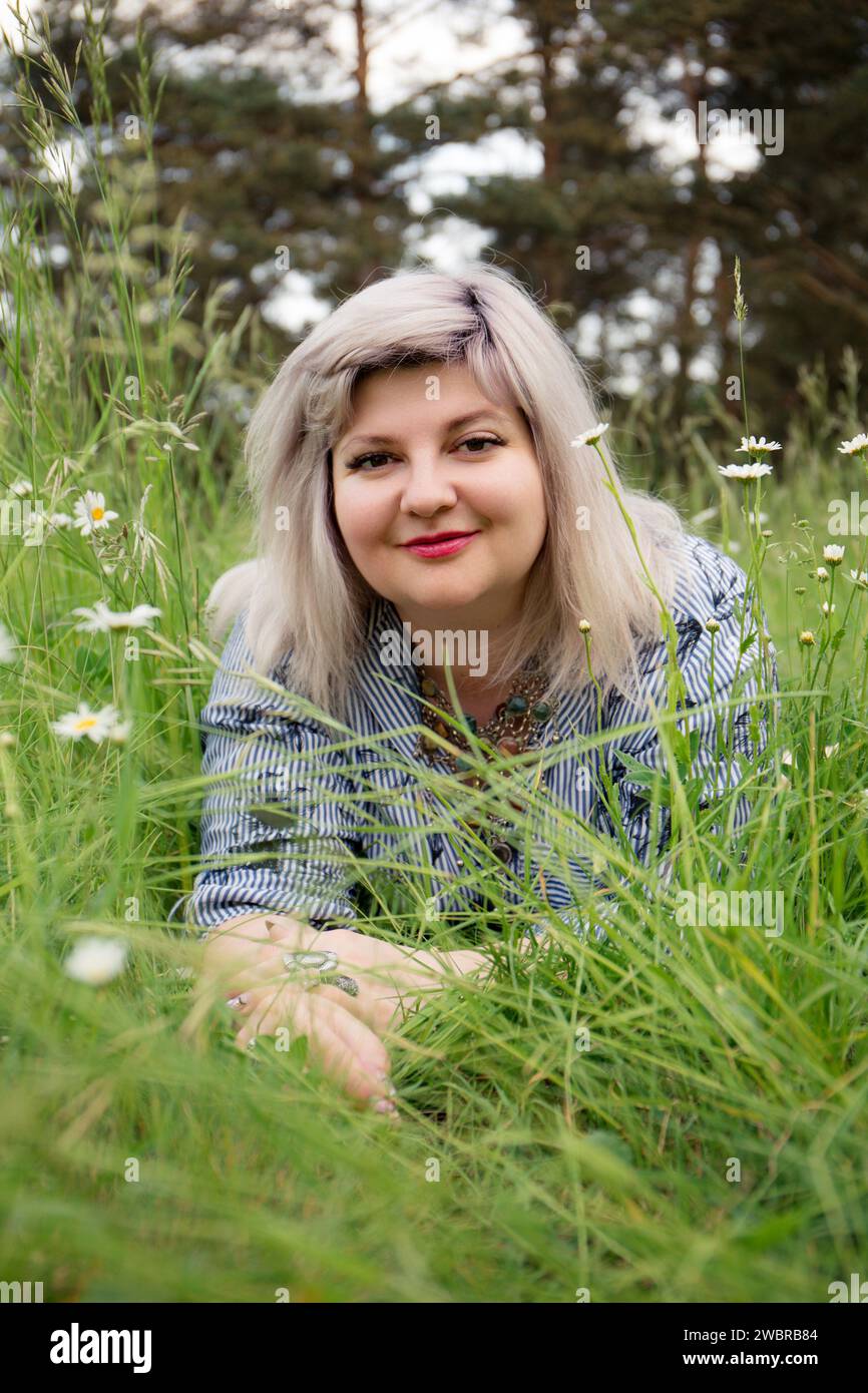 fat woman is lying in the grass Stock Photo