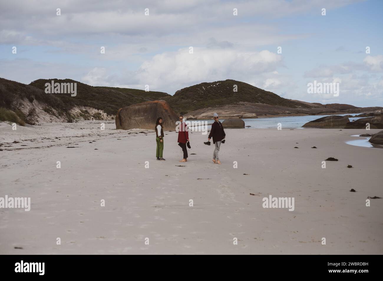 Three friends look back on walk barefoot on remote beach australia Stock Photo