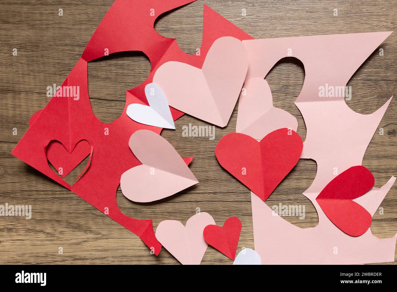 flat lay red and pink paper valentine's cut outs against wood Stock Photo