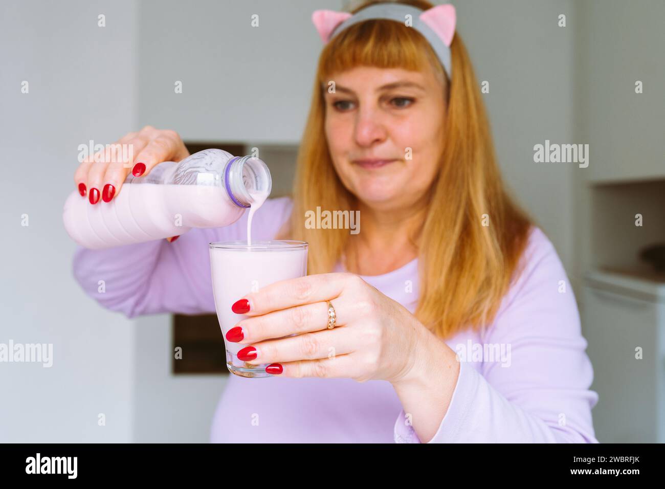 Middle aged woman drinking yogurt Stock Photo