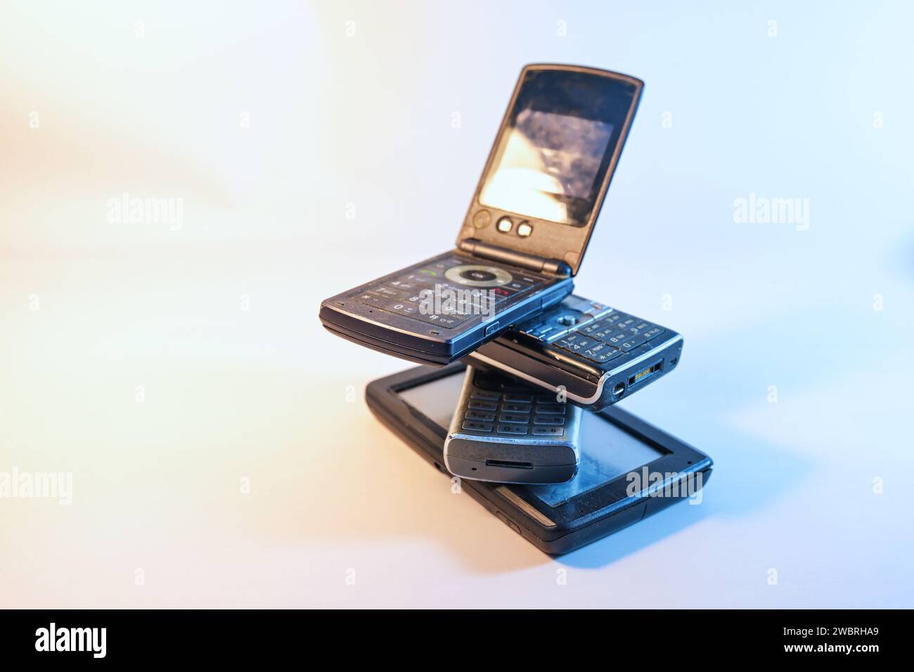 Stack of four old mobile phones, short-lived electronic waste of outdated devices, consumption of valuable resources and difficult to recycle, copy sp Stock Photo