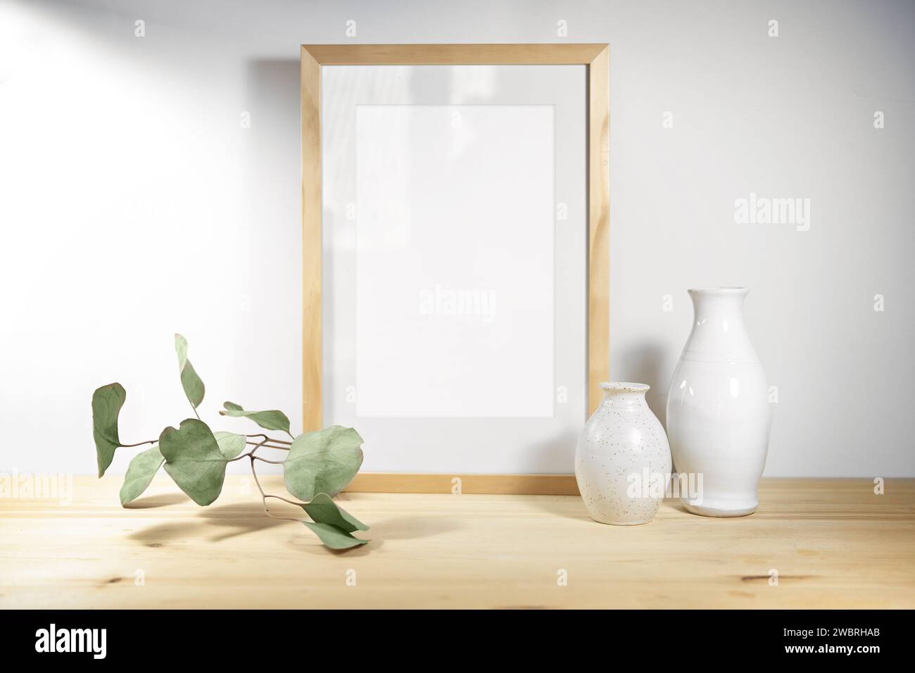 Mockup of an empty picture frame, two white ceramic vases and an