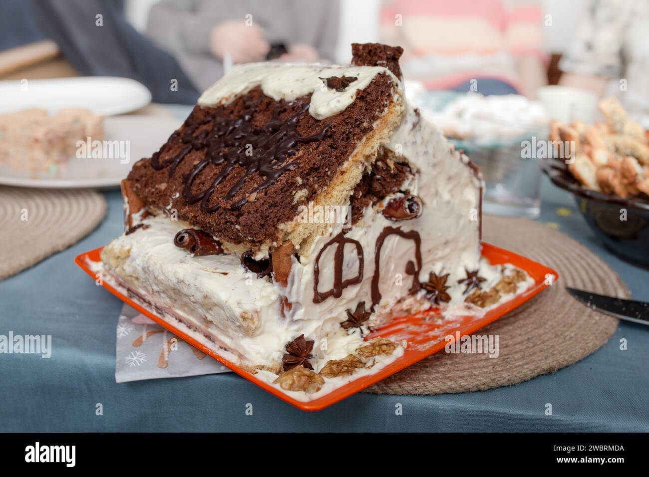 Sponge cake with chocolate and whipped cream made in the shape of a house, soft focus Stock Photo