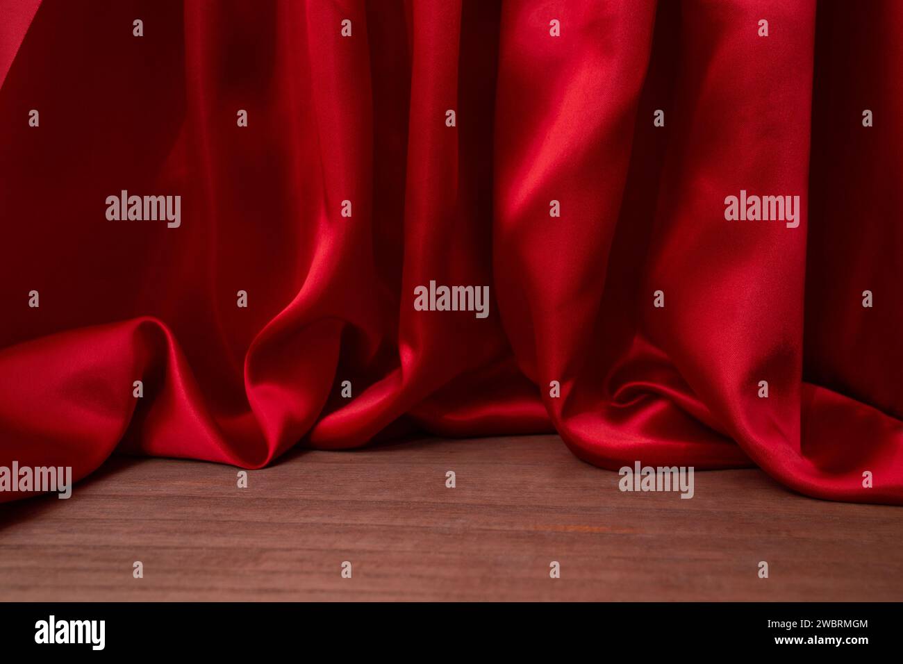 empty wooden floor with Elegant wavy red satin cloth curtains, defocused in the background, product placement  stage Stock Photo