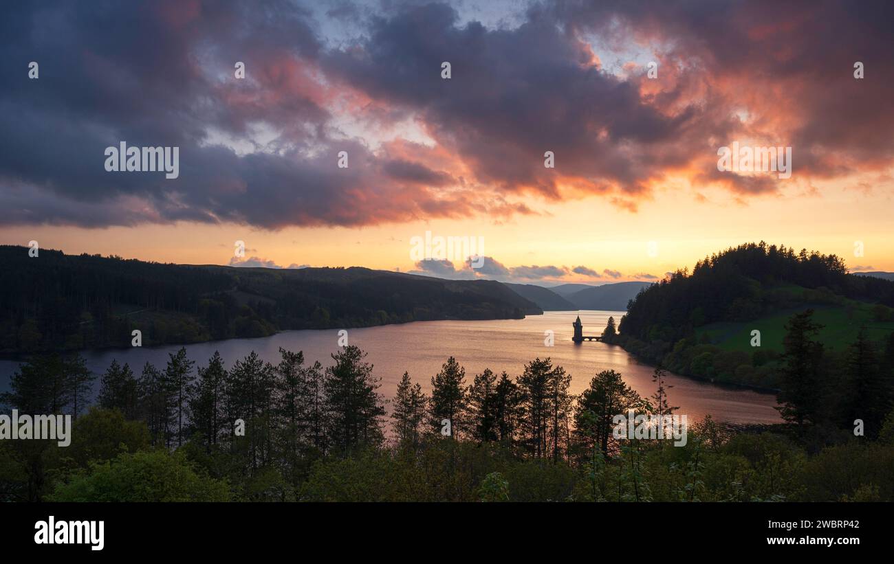 Lake Vyrnwy, located in mid Wales, an area of outstanding natural beauty, at sunset. The orange sky is reflected in the calm water of the lake Stock Photo