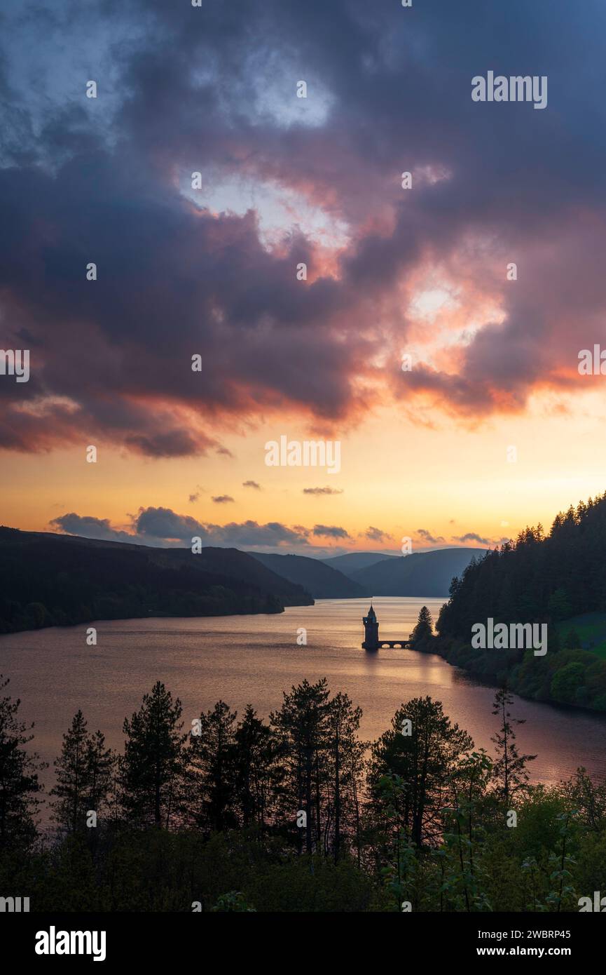Lake Vyrnwy, located in mid Wales, an area of outstanding natural beauty, at sunset. The orange sky is reflected in the calm water of the lake Stock Photo