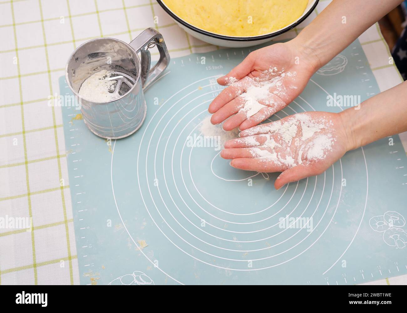 The image shows hands covered in flour over a silicone baking mat. A