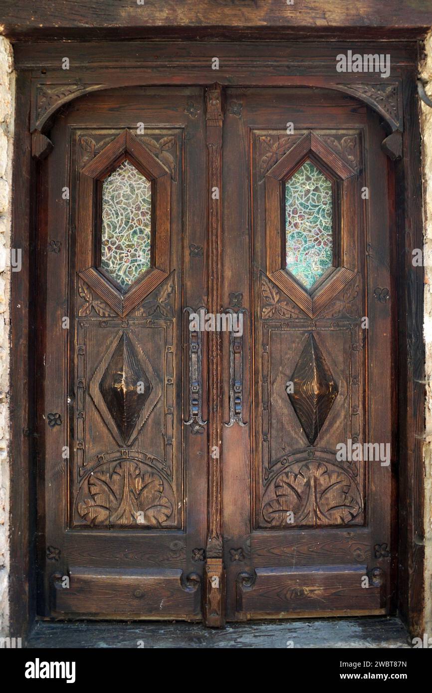 antique, double-leaf, brown entrance door with decor and glass close-up Stock Photo