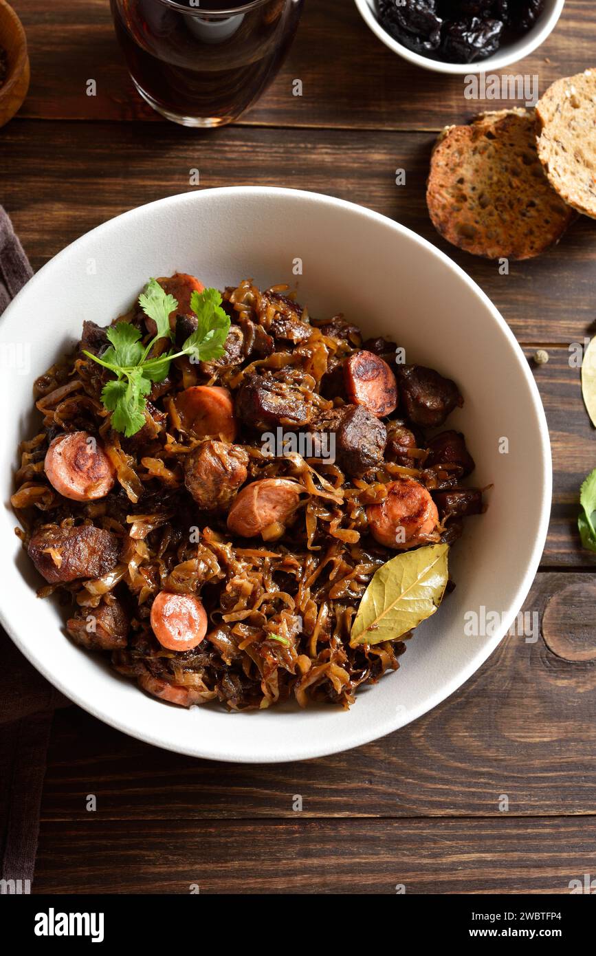 Polish bigos. Stewed cabbage with sauerkraut, mushrooms, smoked meats and spices in bowl on wooden table. Country style, close up view Stock Photo