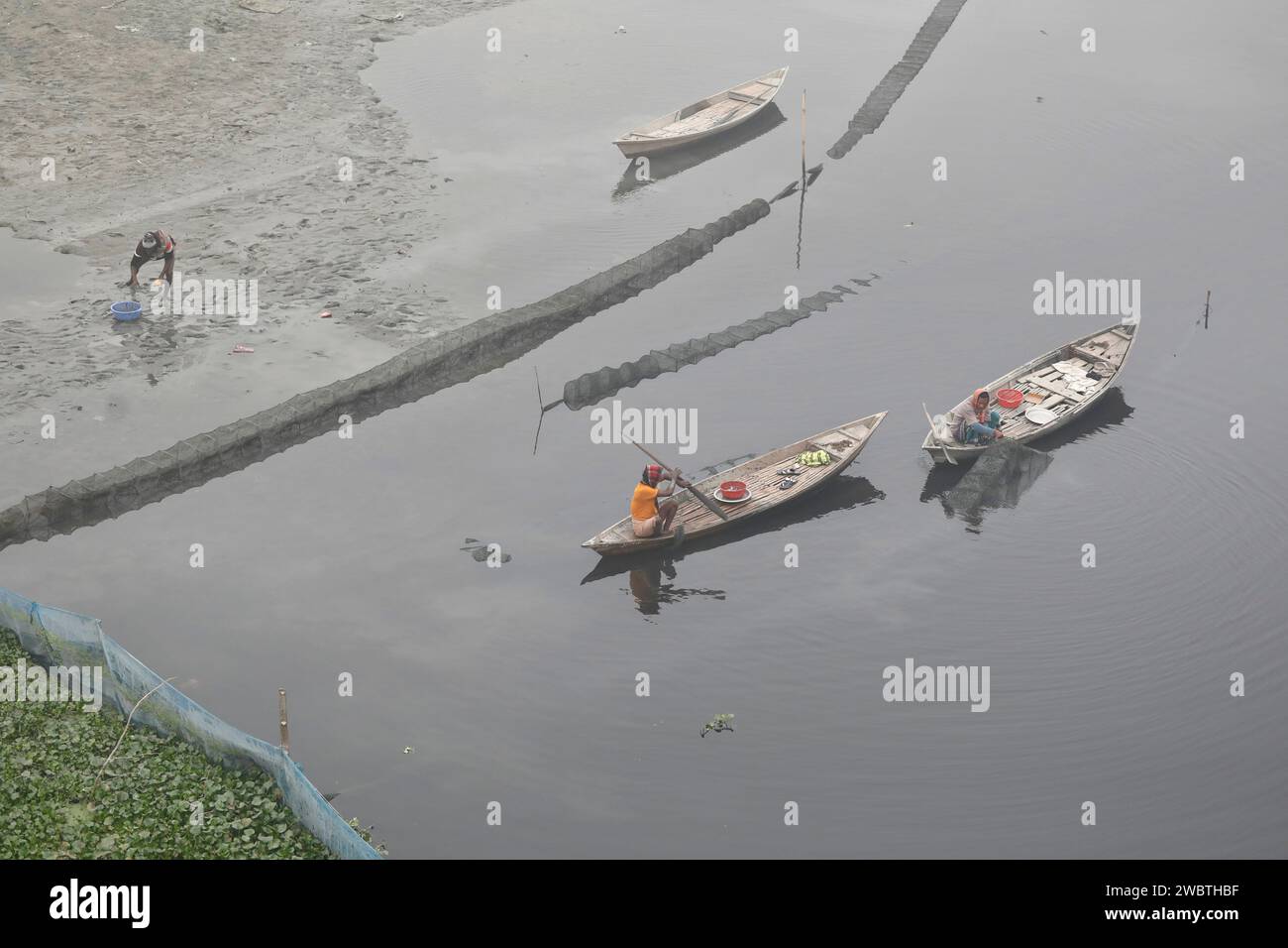 Manikganj, Bangladesh - January 01, 2024: The fishermen fishing in the River in the deep fog of winter morning at Singair in Manikganj. Stock Photo