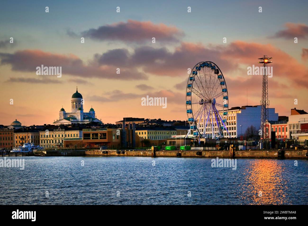 Helsinki cityline and South Harbour seen from ferry at sunset time. Kauppatori and Helsinki Cathedral (Left) and SkyWheel (Right). October 30, 2019. Stock Photo
