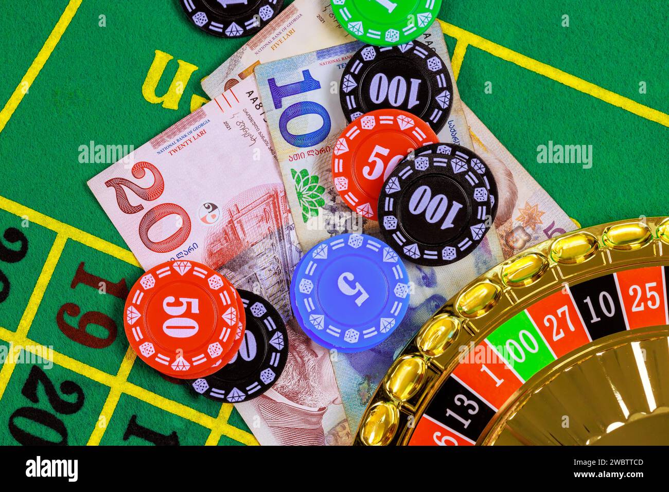 On green gaming table there are roulette, Georgian banknotes in lari poker chips. Stock Photo
