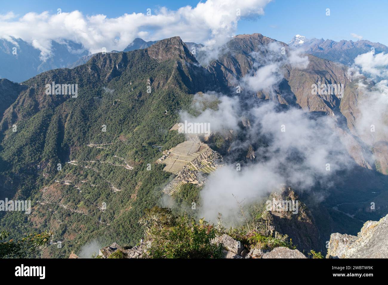 A cloudy and misty view of the Machu Picchu citadel ruins from Huayna Picchu mountain in the Sacred Valley in Peru Stock Photo