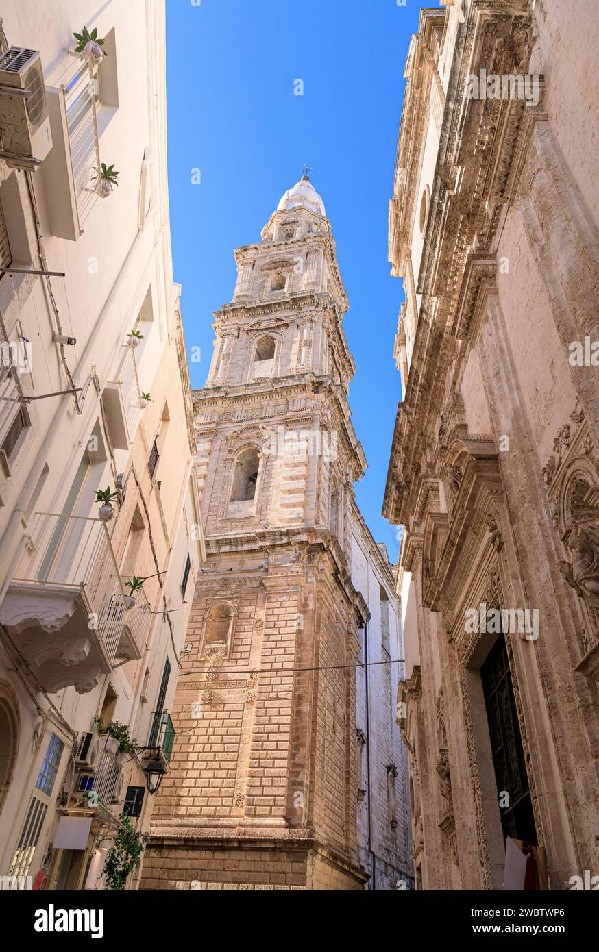 Street view of Monopoli historic center in Apulia, Italy: glimpse of bell tower of Cathedral Maria Santissima della Madia. Stock Photo