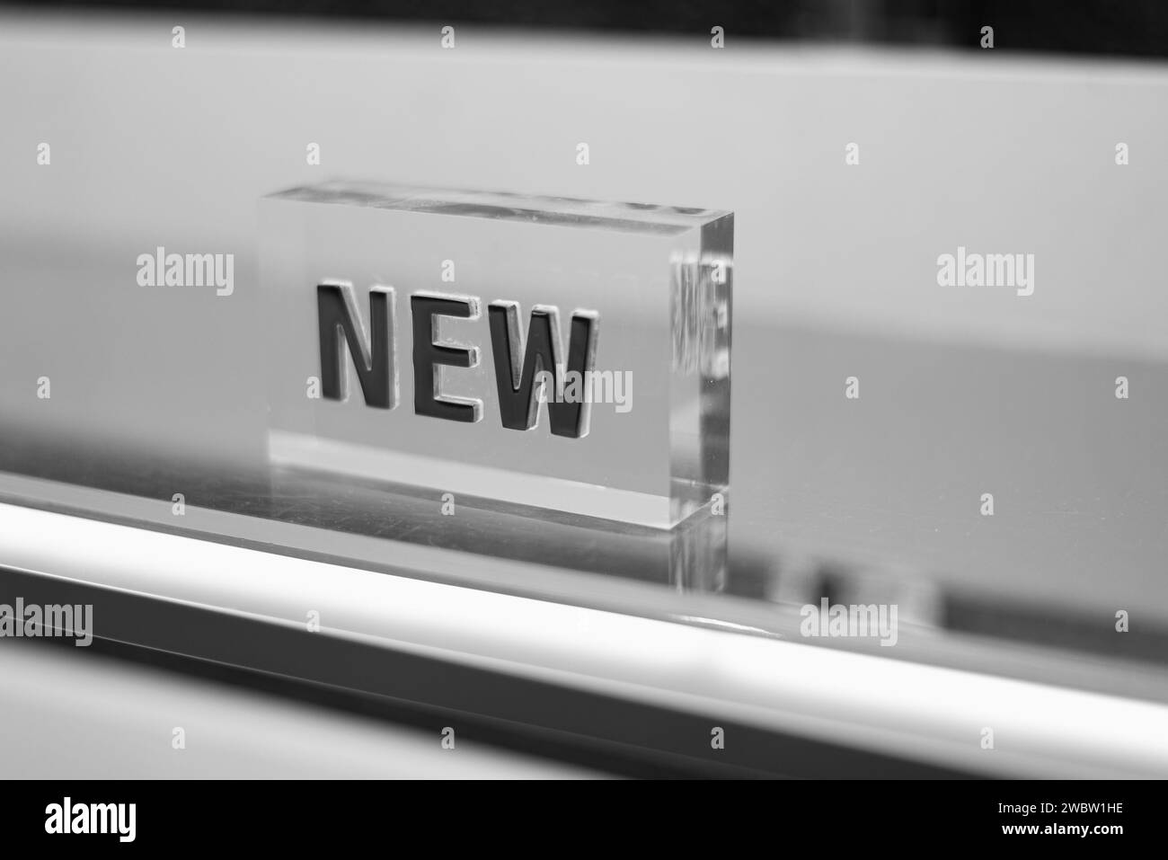 Transparent cube with a three-dimensional inscription New. Selective focus, black and white, concept. Stock Photo