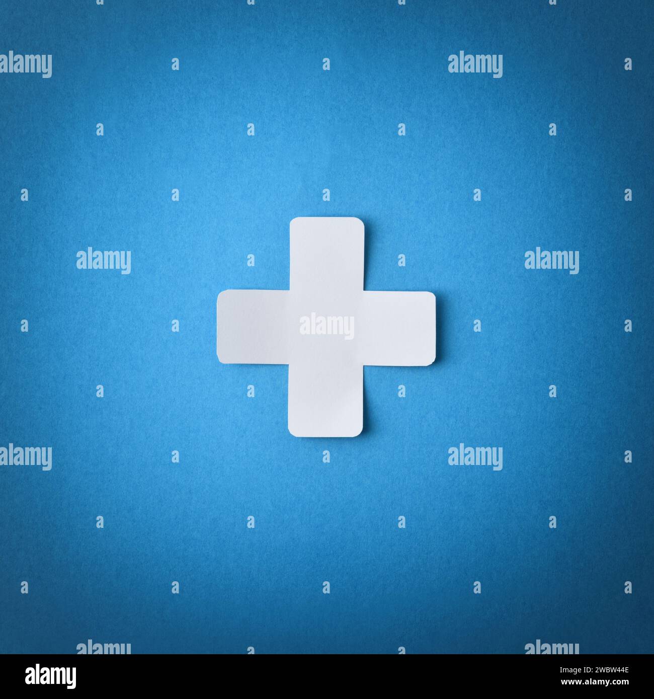 Conceptual symbol with cross shaped paper cutout isolated in the center on blue background. Square composition Stock Photo