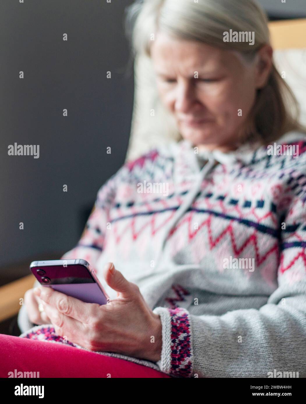A hard working self-employed female,sits in an armchair,in her house,using a mobile phone to leisurely chat to an old friend, and takes time to relax, Stock Photo