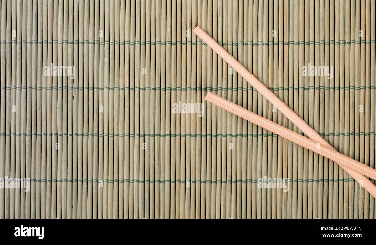 A top-down view of a bamboo mat with an assortment of Chinese food and traditional chopsticks, showcasing the vibrant colors and textures of the cuisi Stock Photo