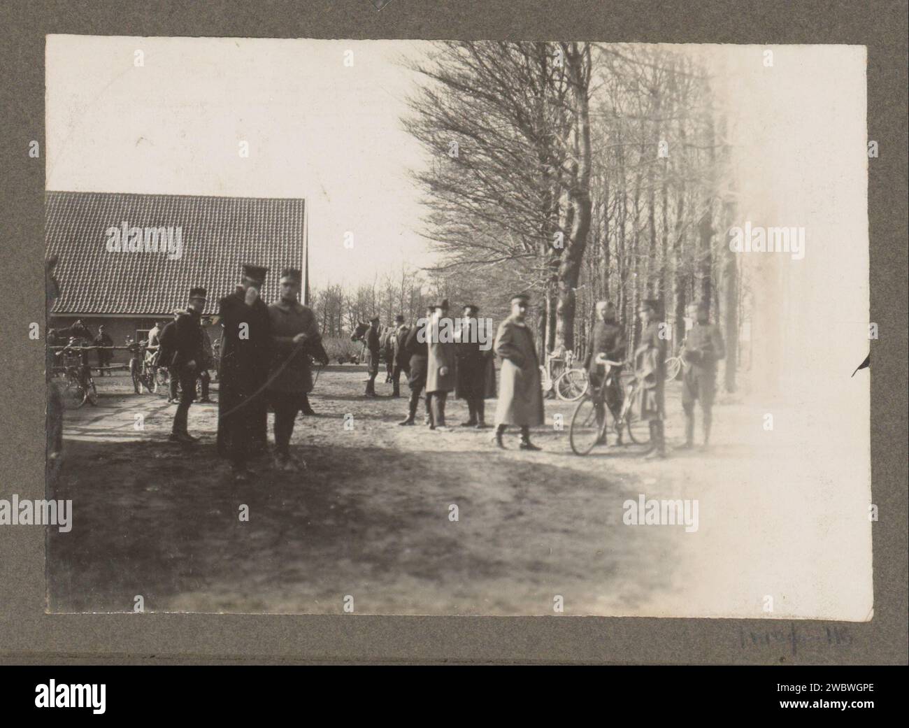 Ranger scene at the Royal Houtvesterij Het Loo: uniformed men with bicycles near a barn, anonymous, c. 1900 - c. 1925 photograph Part of the photo album of Mr Brams, Opperhoutvester by Queen Wilhelmina at the Royal Houtvesterij Het Loo. Royal Houtvesterij Het Loo photographic support gelatin silver print hunting, chase. hunting-ground. (military) uniforms. bicycle Royal Houtvesterij Het Loo Stock Photo