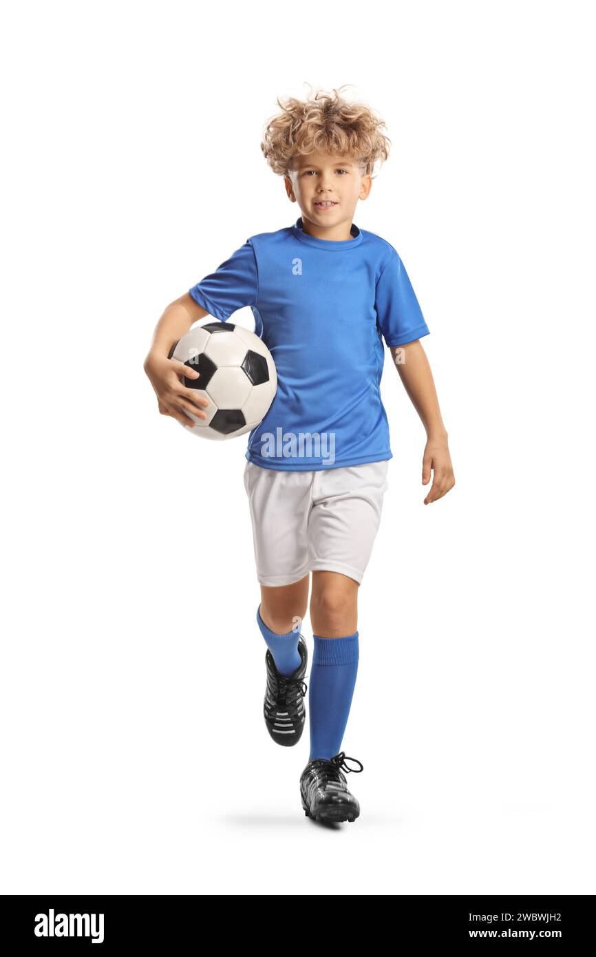 Full length portrait of a boy in a football kit running and carrying a ball isolated on white background Stock Photo