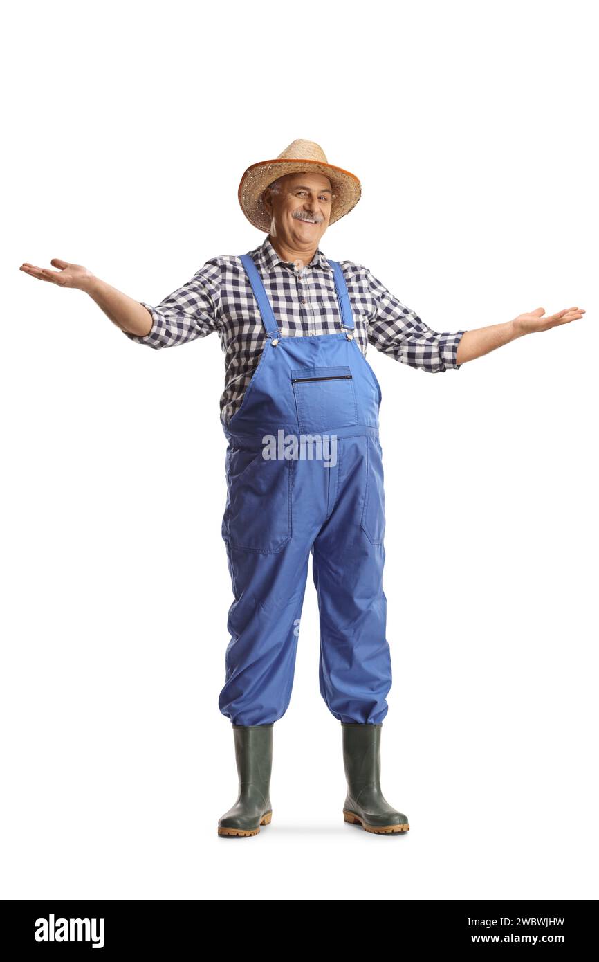 Full length portrait of a mature farmer in blue overalls gesturing welcome isolated on white background Stock Photo