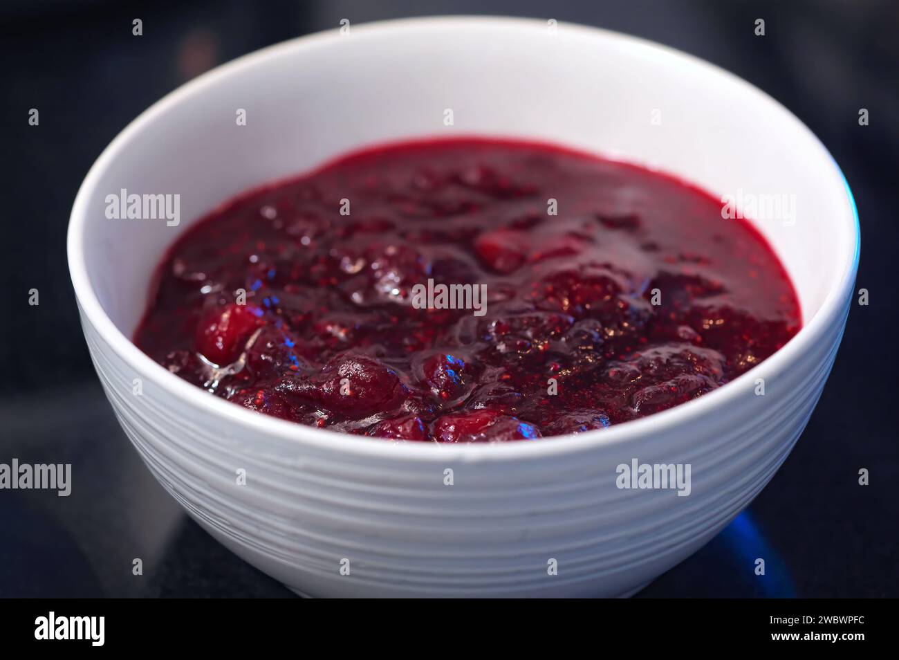 Cranberry Sauce or Jam (Vaccinium macrocarpon) in a white bowl with dark background. Stock Photo