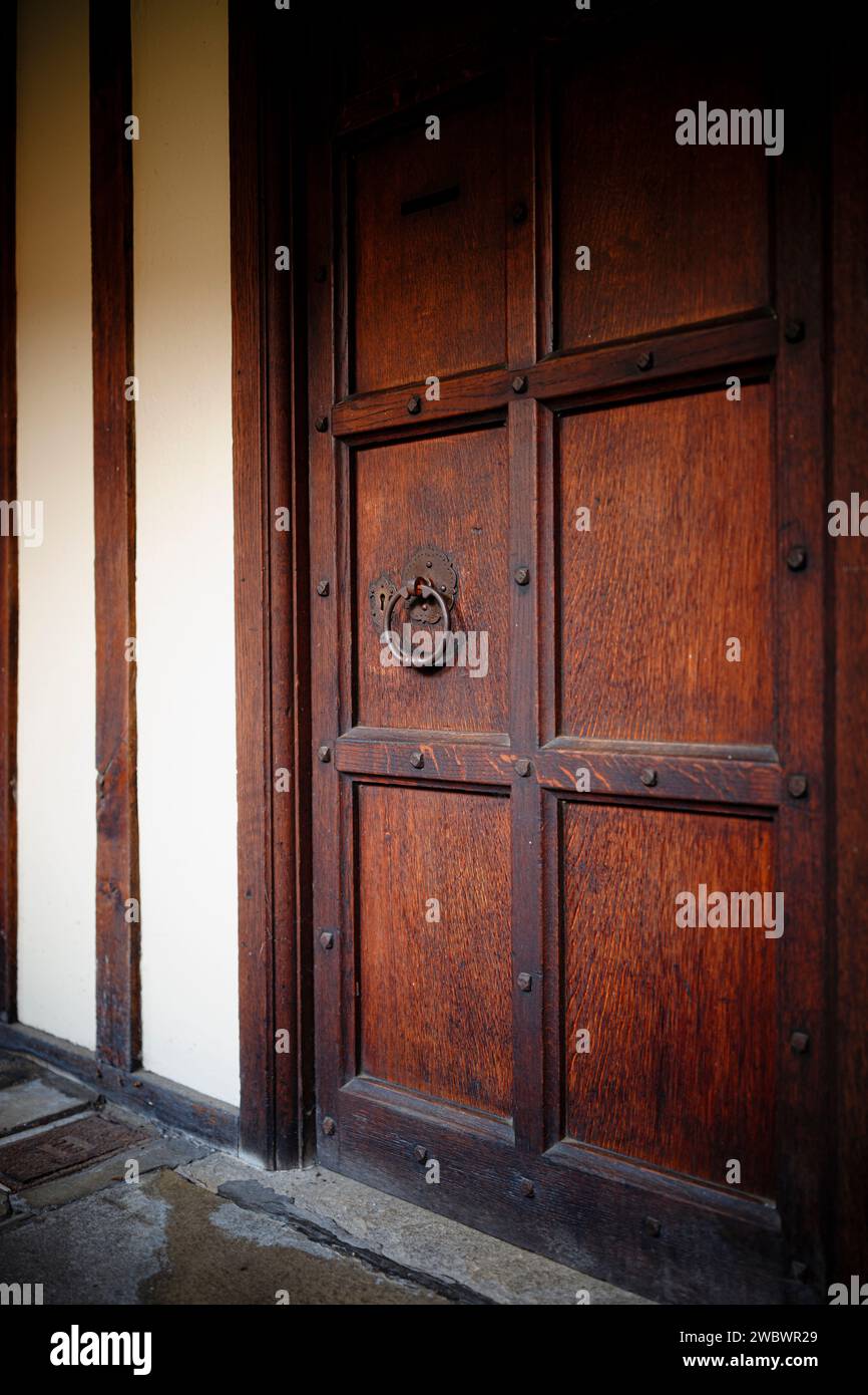 This vintage wooden door features intricate carvings and a stately brass door knocker Stock Photo