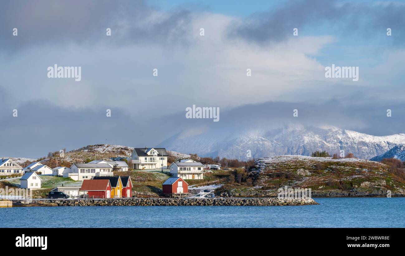rote und gelbe Häuser am Strand des Atlantik auf der Insel Hillesøya bei Sommarøy, Troms, Norwegen. Landschaft Kalenderfoto mit Bergen im Hintergrund Stock Photo