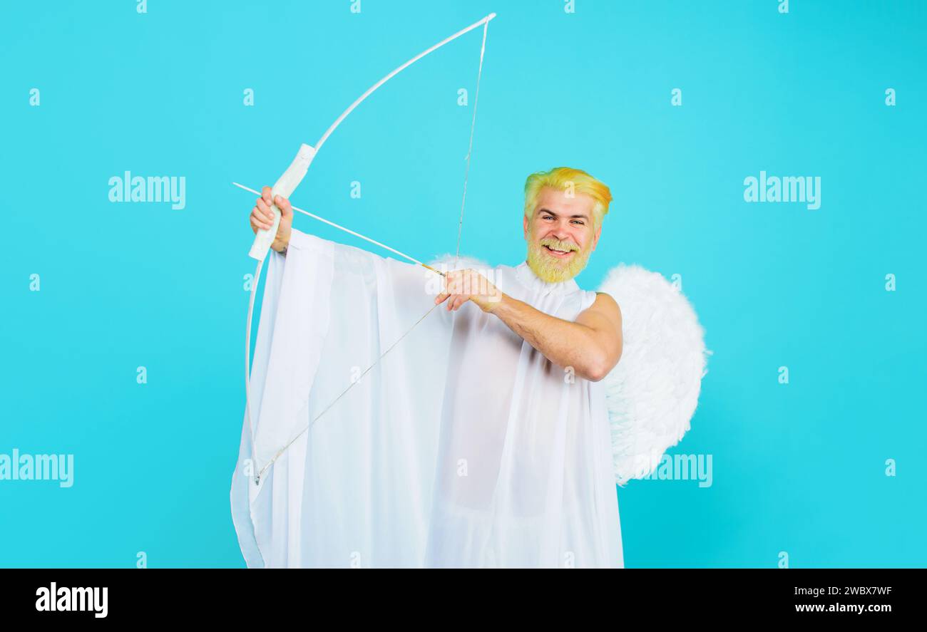 Valentine cupid angel shooting arrows of love. Smiling bearded man in angel costume with bow and arrow. God of love. Male cupid in angel wings shoots Stock Photo