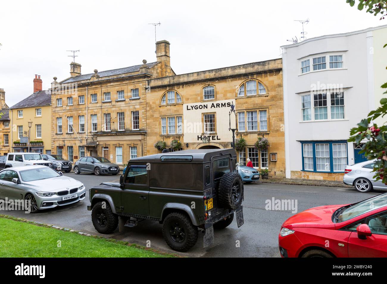 Chipping Campden town centre, Lygon Arms Hotel on high street with green Land Rover Defender parked across the road,Cotswolds,England,UK Stock Photo