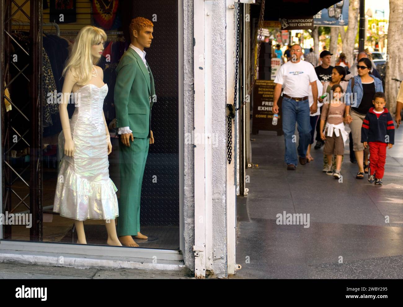 Visitors walking on Hollywood Boulevard near a shop with a window