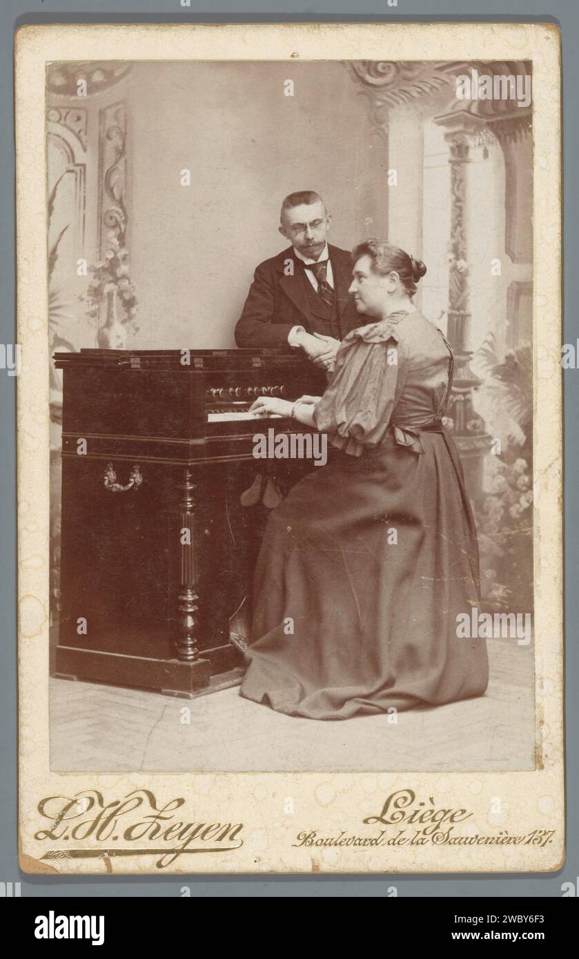 Portrait of an organ -playing woman and a watching man, Léonard Hubert Zeyen, c. 1890 - In or Before 1915 cabinet photograph  Shutter cardboard. photographic support  organ. musician at work Stock Photo